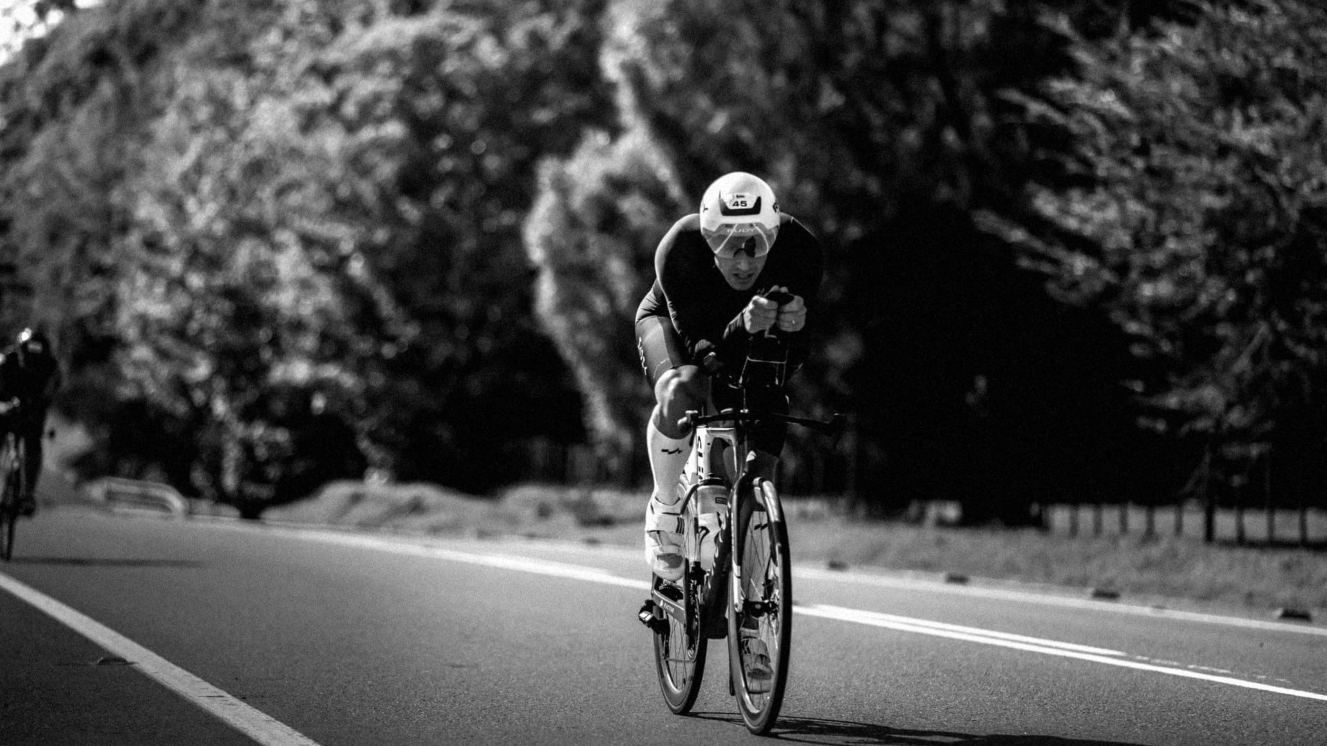 Triatleta en contrarreloj por un camino entre árboles